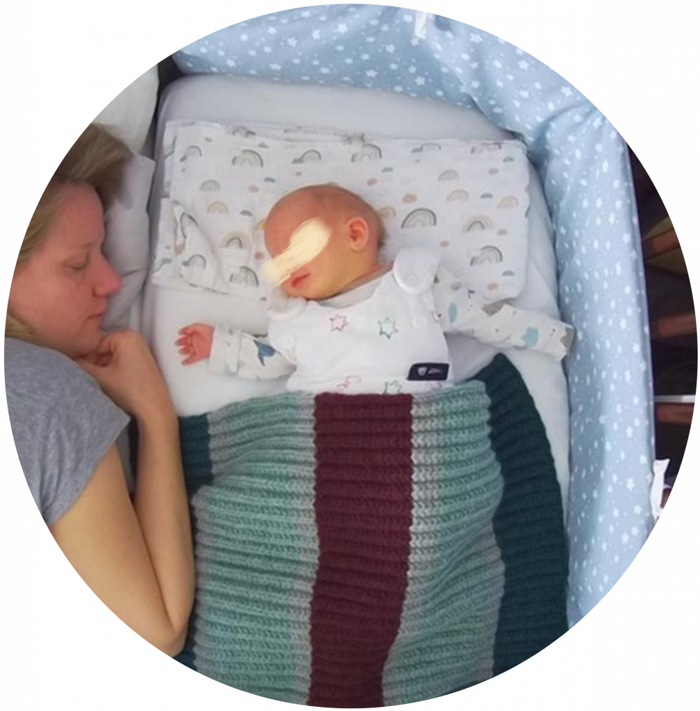 Eine Frau schläft im Bett neben ihrem Säugling